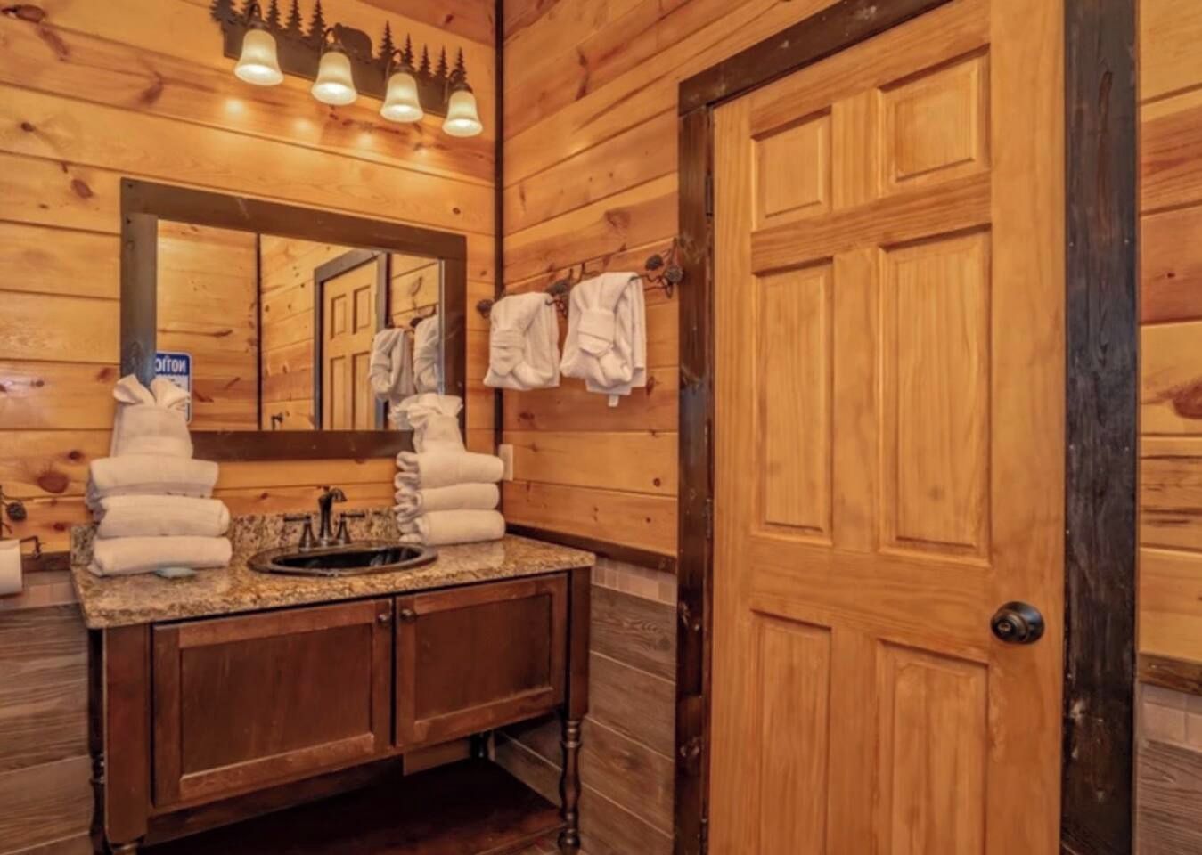 A wooden bathroom with a sink, mirror, and towels.