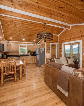 A spacious wooden interior with a dining area, sofa, and kitchen. - Smoky Mountain View | Pickleball | Family Retreat (Gatlinburg)