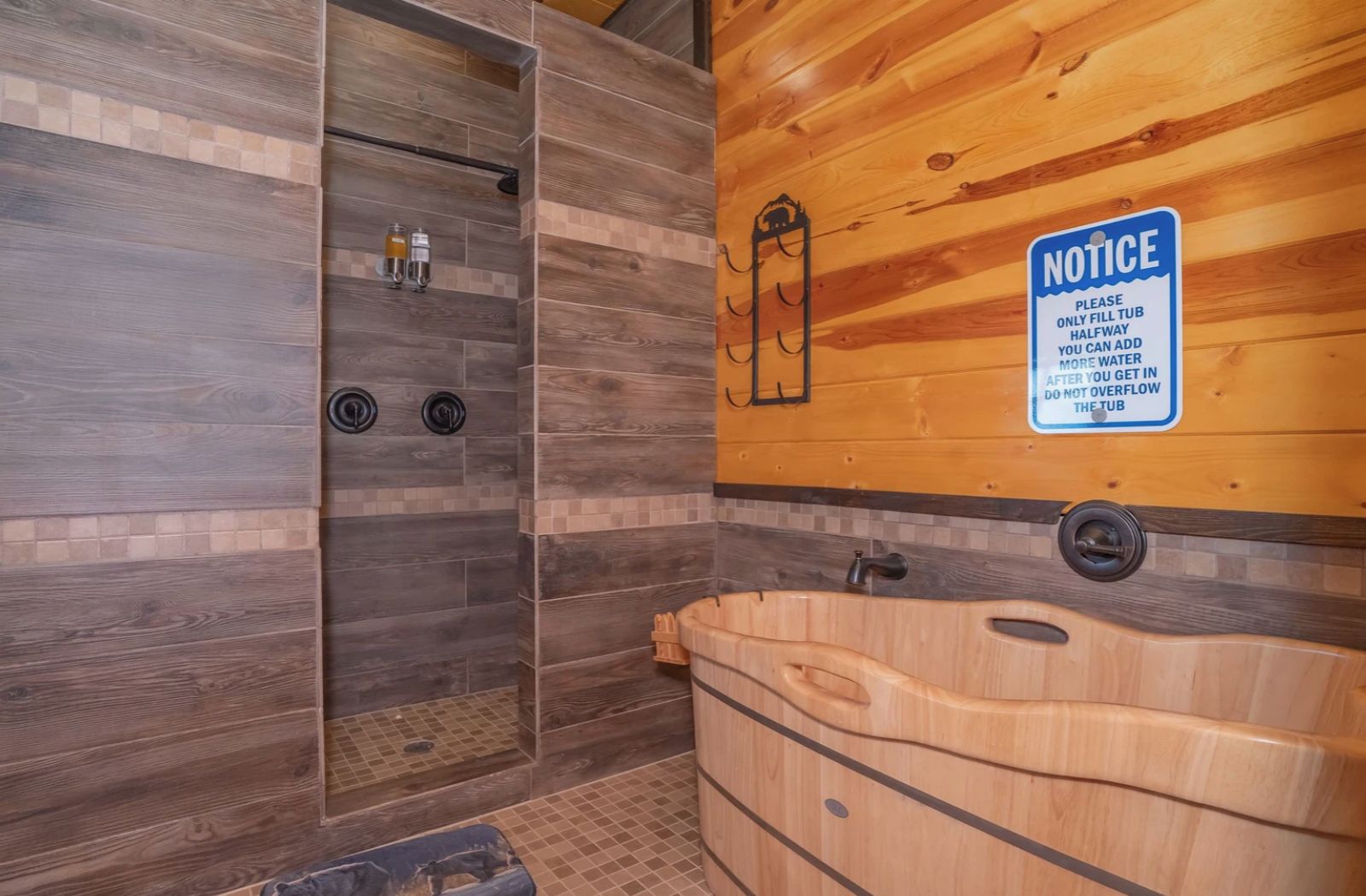 Een houten badkamer met een houten bad, een douchecabine en een bord met meldingen.