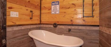 Une salle de bain avec une baignoire sur pieds, des murs en bois et un panneau d’information.