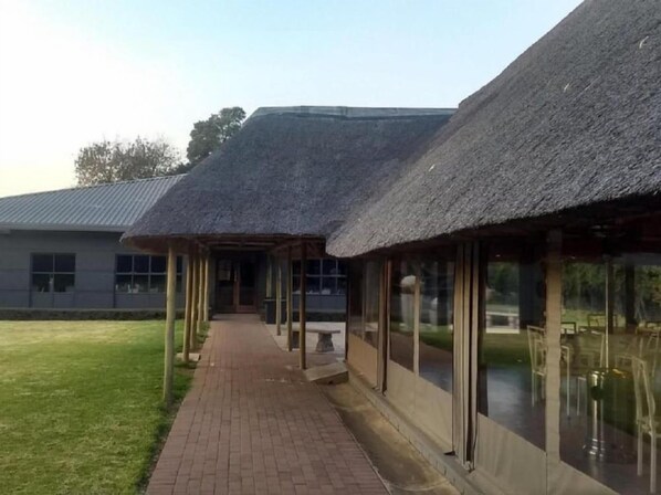 Een gebouw met een pad van bakstenen dat leidt naar een overdekt gebied met rieten daken.