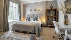 A bedroom with a bed, bedside tables, a desk, and a chair. - Carmel Apartments (Falkirk)
