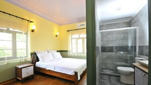 A bedroom with a wooden bed, a nightstand, and a window with sheer curtains. - Petrino Gokceada Hotel (Gökçeada)