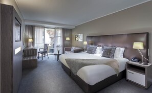 Hotellihuone, jossa on suuri sänky, työpöytä, tuoli ja pieni pöytä.