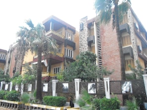 Un edificio residencial de varios pisos con balcones, fachada de ladrillo y entrada protegida por una reja.
