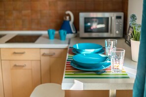 Een keuken met een magnetron, een waterkoker en een geruit tafelkleed.