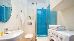 Une salle de bain moderne équipée d’un lavabo, de toilettes, d’une douche et d’un lave-linge.