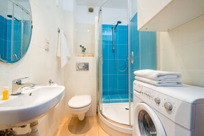 A modern bathroom with a sink, toilet, shower, and a washing machine. - P&O Waszyngtona (Warsaw)