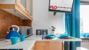 Une cuisine équipée d’un plan de travail, d’une bouilloire, de tasses, d’un four à micro-ondes et d’une enseigne indiquant « P&O Apartments ».