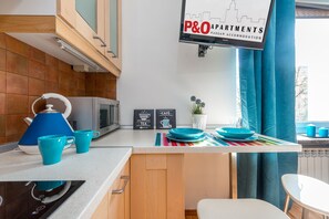 A kitchen with a countertop, a kettle, cups, a microwave, and a sign for P&O Apartments. - P&O Waszyngtona (Warsaw)