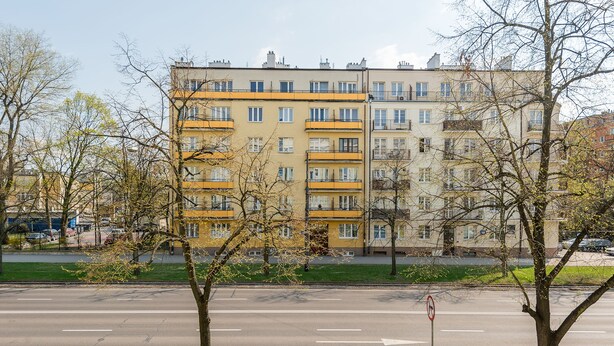 Un immeuble résidentiel à plusieurs étages, doté de balcons et offrant une vue dégagée sur la rue.