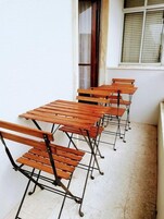 Fileira de mesas e cadeiras de madeira, com estrutura metálica, dispostas em um ambiente de sala de aula ou reunião.