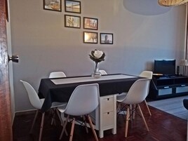 Uma área de refeições com mesa, cadeiras e um vaso com uma flor.