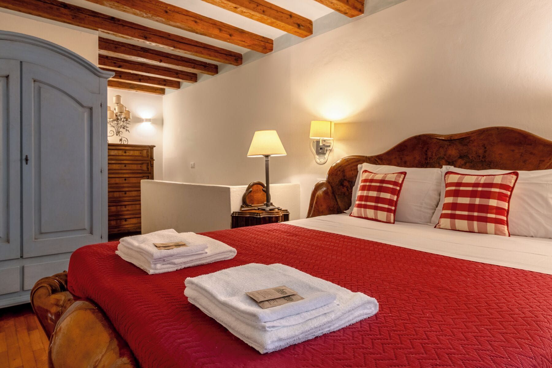 Una habitación de hotel con cama, mesita de noche, lámpara y armario.
