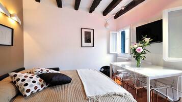 Un dormitorio con cama, escritorio y silla. Se aprecia una ventana con vistas al exterior.