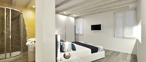 Une chambre moderne comprenant un lit, une table de chevet, un téléviseur et un espace douche.