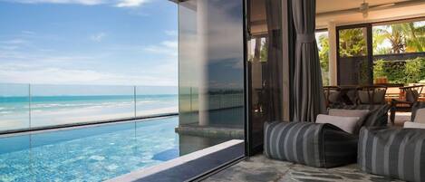 A modern interior with a glass balustrade overlooking a beach.
