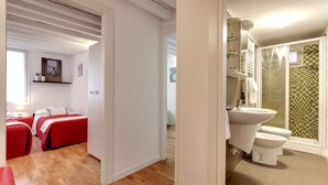 Habitació d'hotel amb un llit, una taula de nit, un mirall i un bany amb rentapans i vàter.