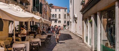A narrow street with outdoor seating and a café on one side.