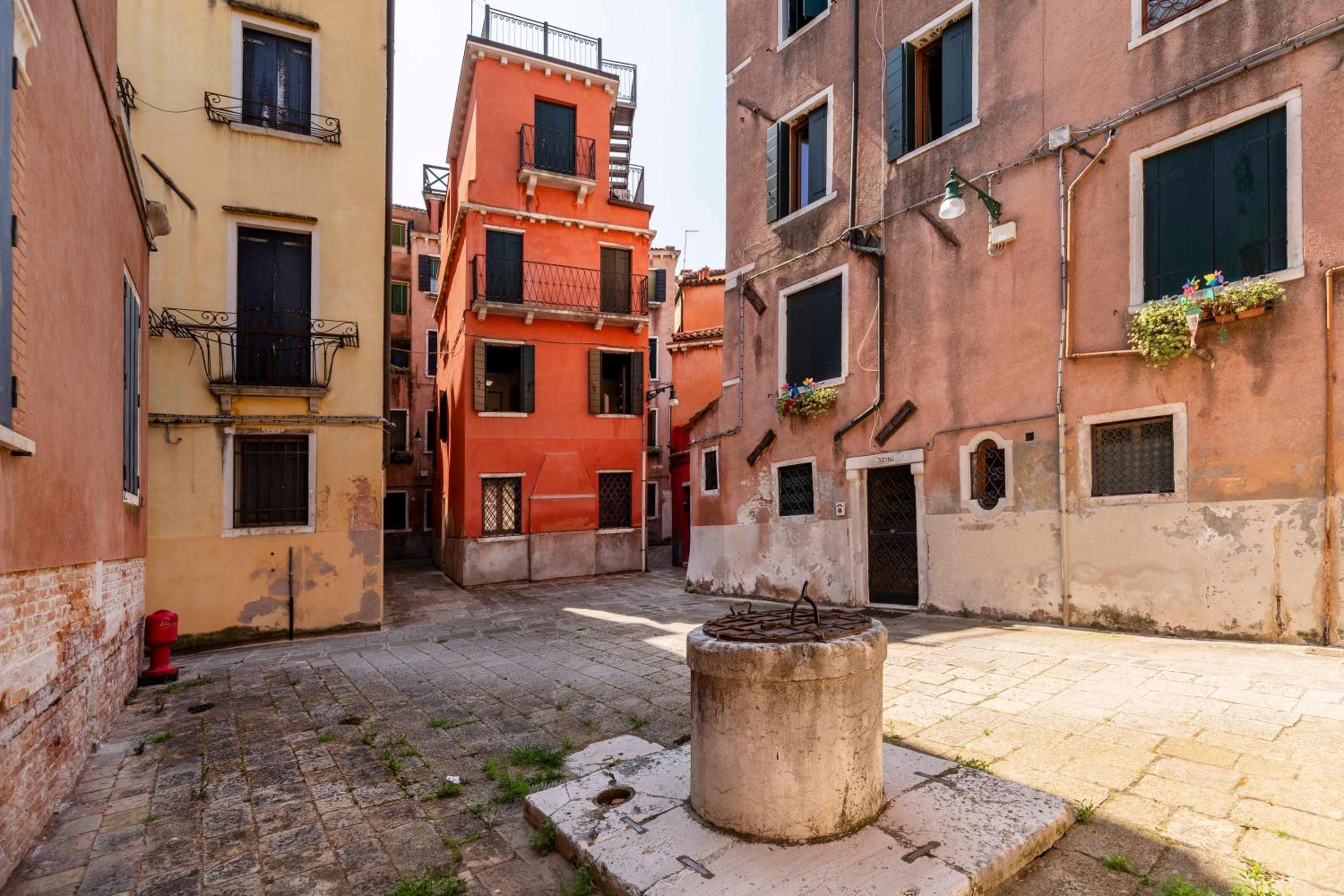 Une ruelle étroite, bordée de bâtiments des deux côtés, avec une borne d’incendie et un poteau de protection en béton.