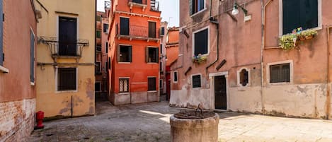 A narrow alleyway with buildings on either side, a fire hydrant, and a concrete bollard.