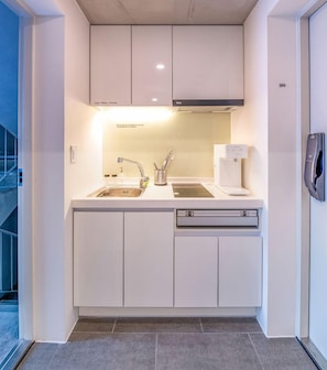 A modern kitchen with white cabinetry, a stainless steel sink, and a built-in oven. - Le Lit (Seoul)