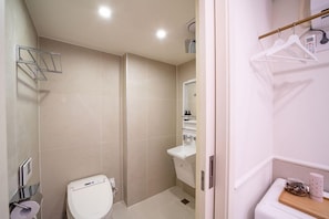 A bathroom with a toilet, a shower, and a sink.