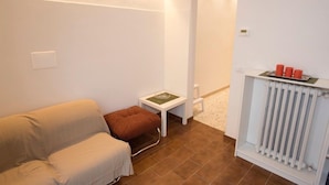 A room with a sofa, a small table with a book, a radiator, and a door leading to another room.