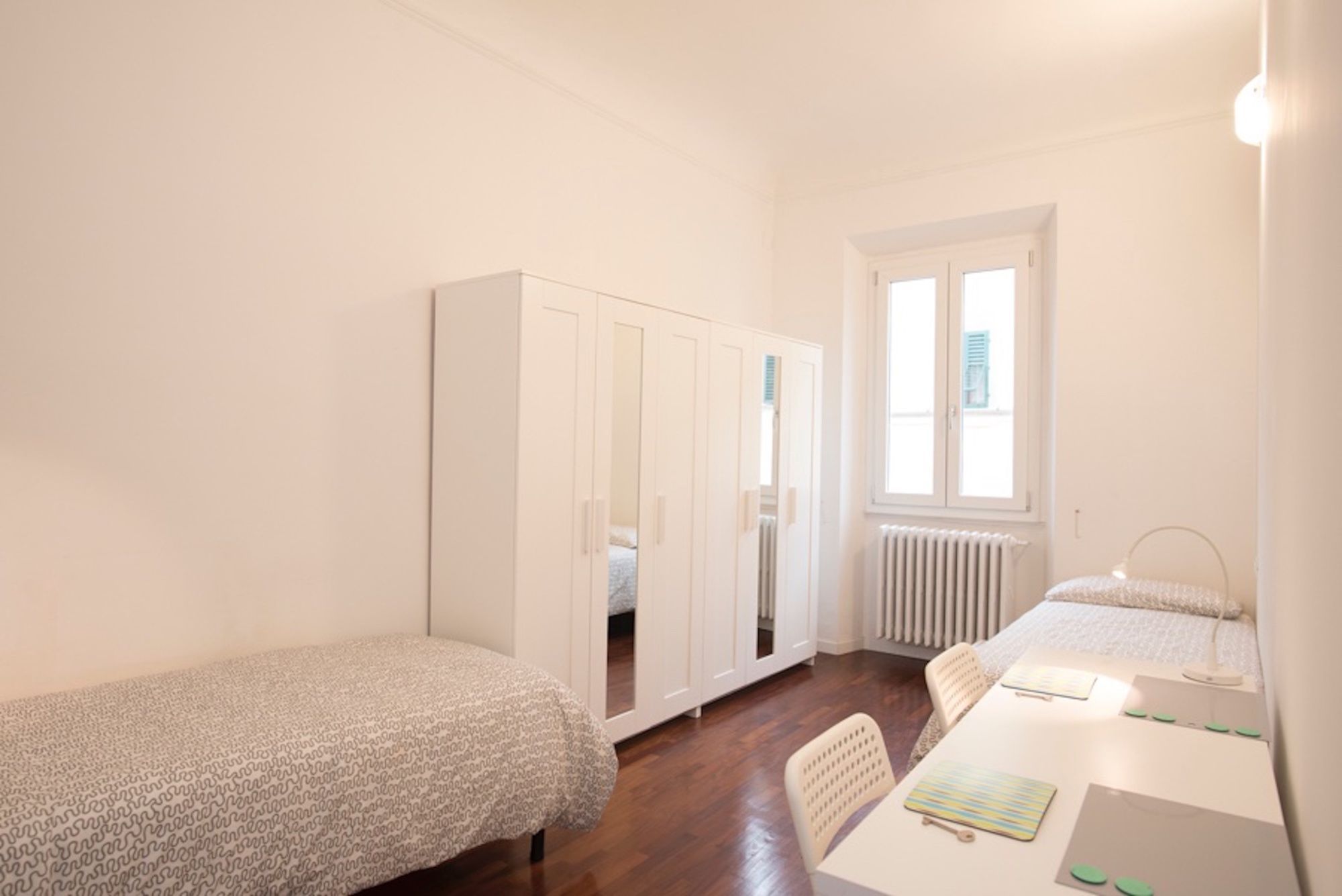 A bedroom with a single bed, a desk with a chair, and a wardrobe.