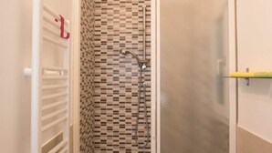 A shower enclosure with a checkered tile pattern, a white toilet, and a towel rack.