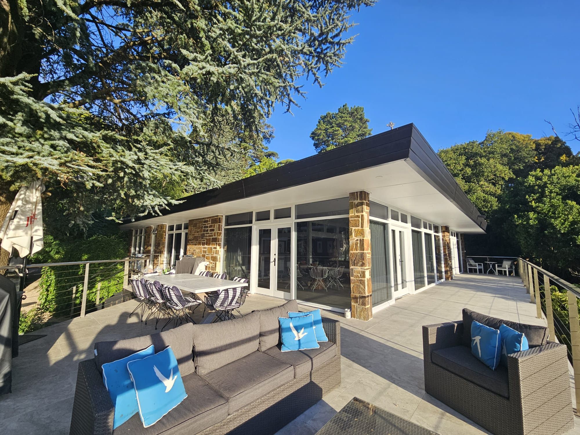 A modern building with a covered patio area, outdoor seating, and a stone facade.