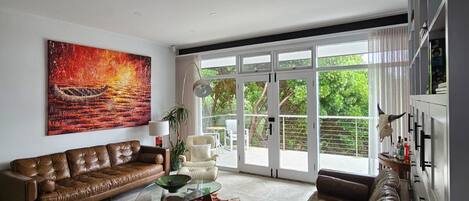 A modern living room with a leather sofa, a glass coffee table, and a large painting.