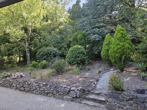 A garden with a stone pathway, various shrubs, and trees. - Breathtaking house in Crafers West - sleeps 10 (Crafers West)