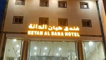 A hotel with a sign in Arabic and English, multiple floors, and a glass facade.