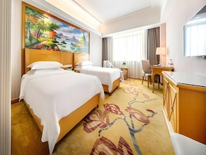 A hotel room with two beds, a desk, a chair, a TV, and a large painting on the wall. - Viennahotel Banxuegang Road (Shenzhen)