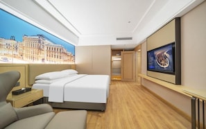 A hotel room with a bed, a desk, a chair, a TV, and a cityscape view. - Viennahotel Banxuegang Road (Shenzhen)