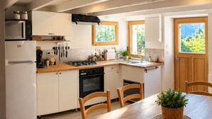 Eine Küche mit einem Holztisch, Stühlen, einem Herd, einem Backofen, einer Mikrowelle und Schränken.
