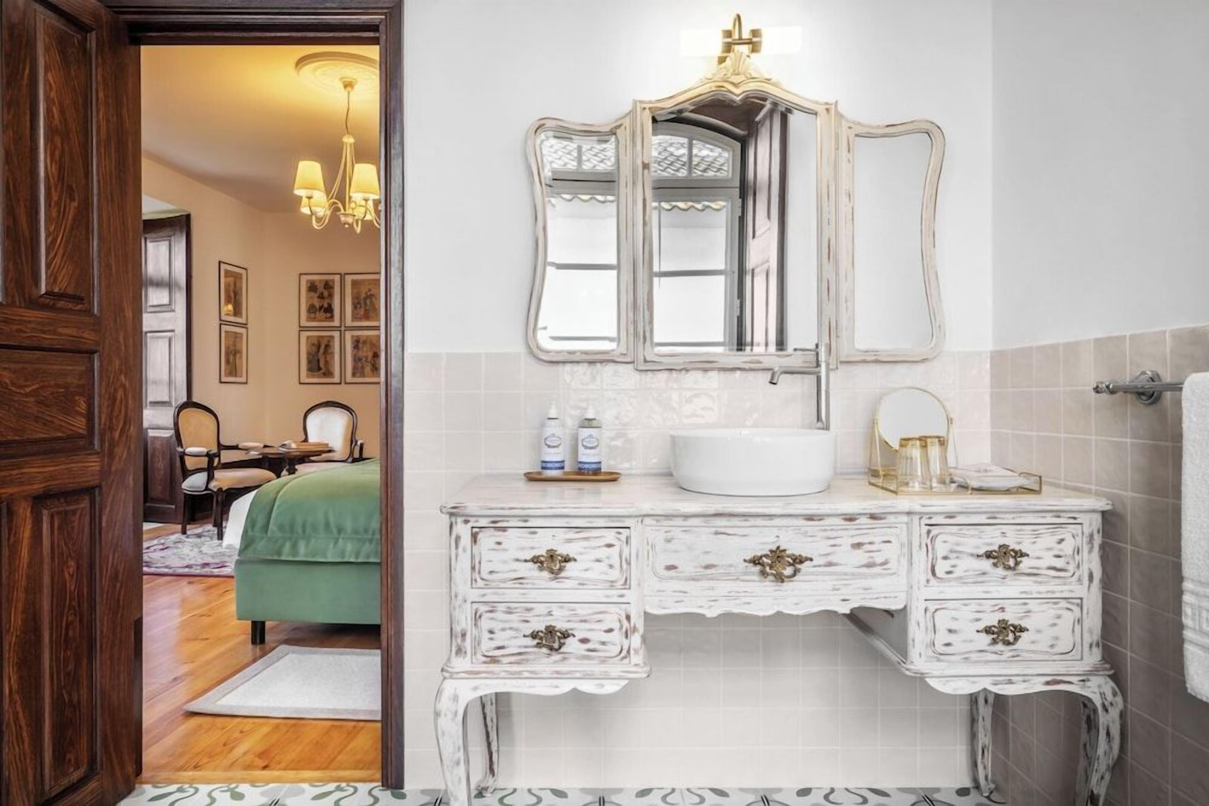A bathroom with a white vanity, a large mirror, and a chandelier.