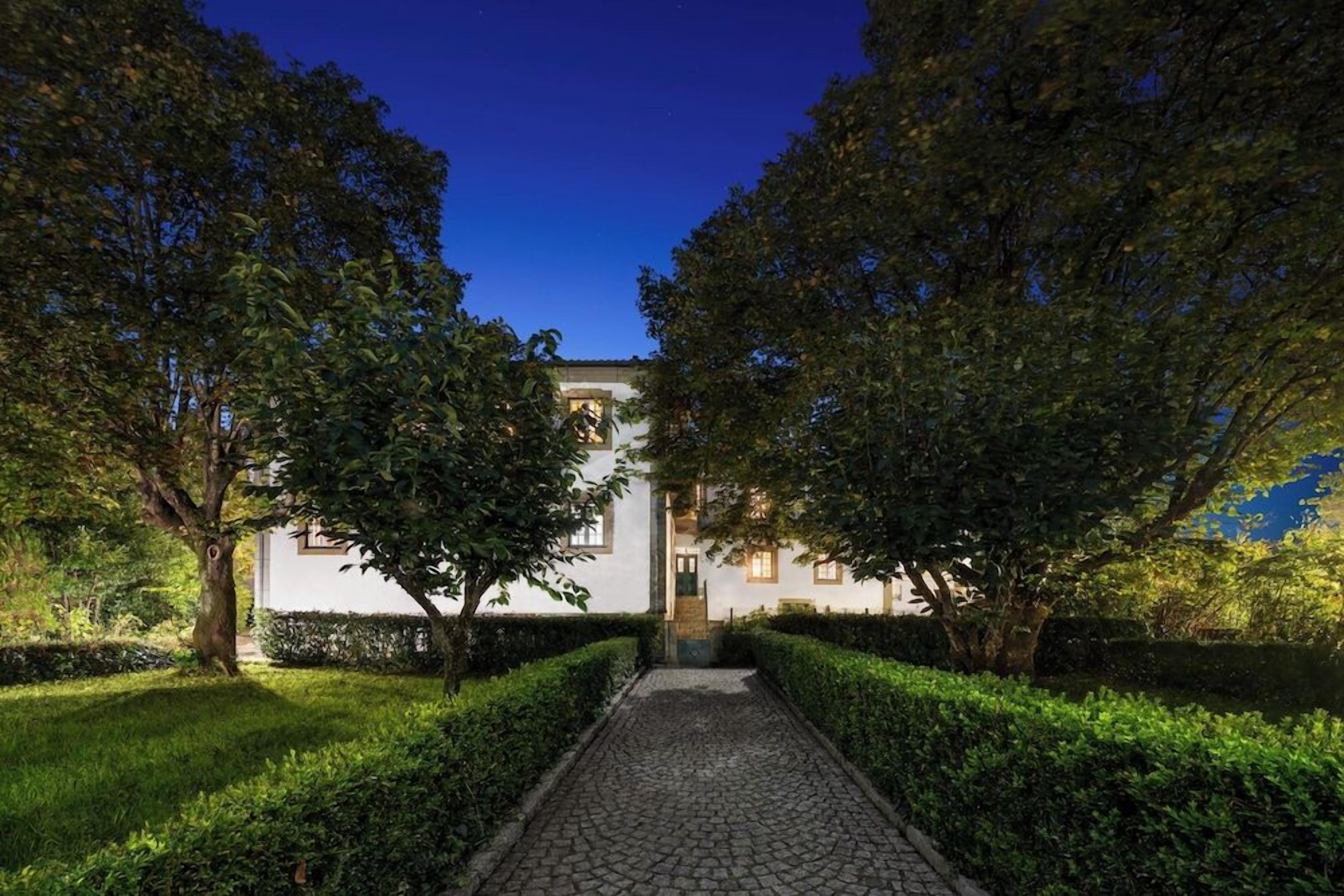 A pathway leading to a building surrounded by trees and hedges.
