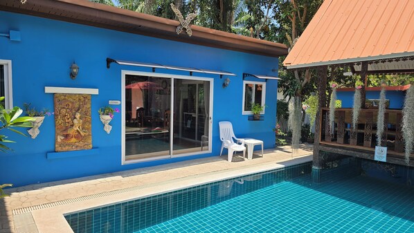 Un bâtiment bleu avec une piscine, une chaise blanche et un panneau indiquant qu’il est interdit de sauter dans la piscine.