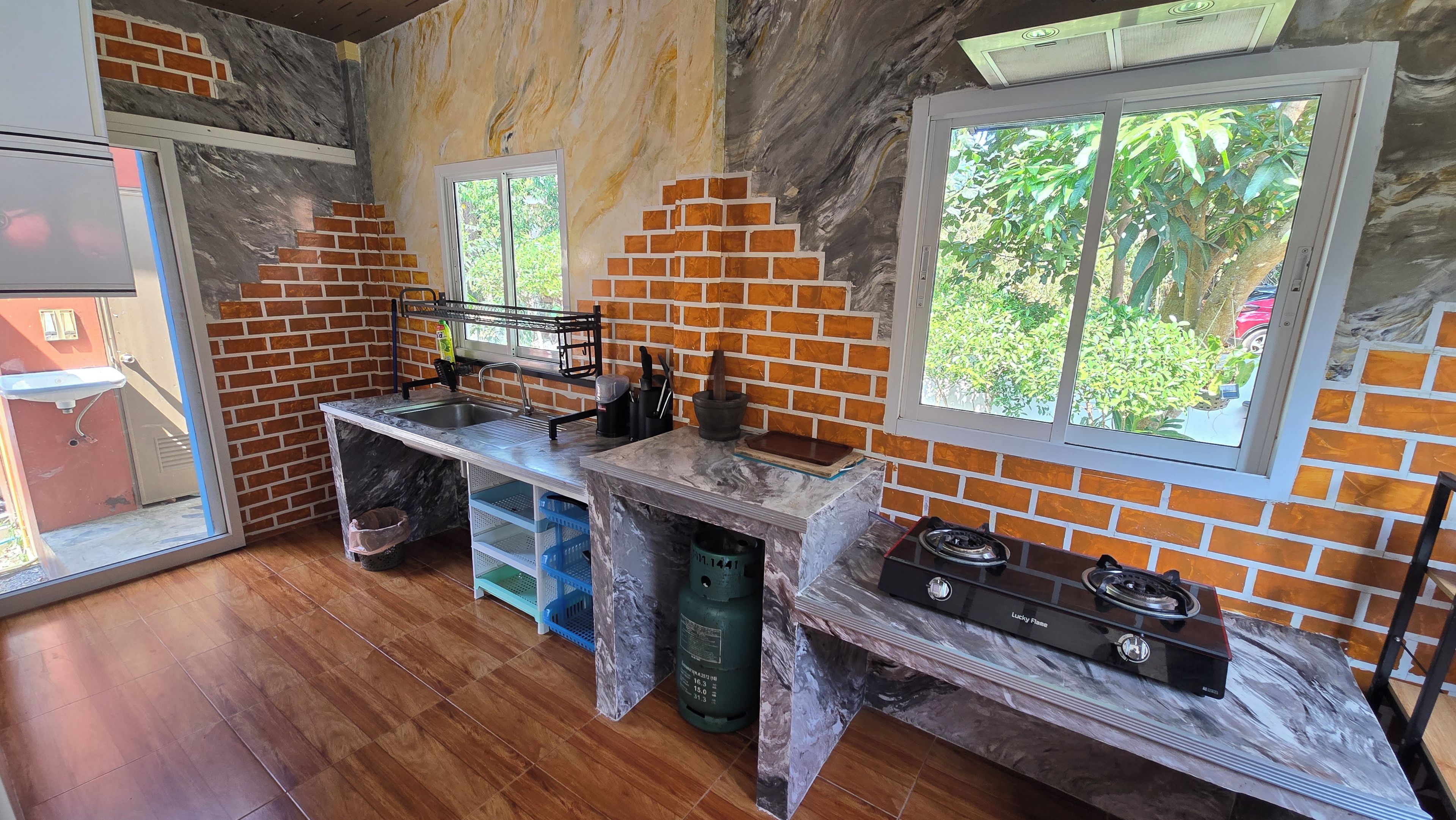 A kitchen with a marble countertop, a gas stove, and a window with a view of greenery.