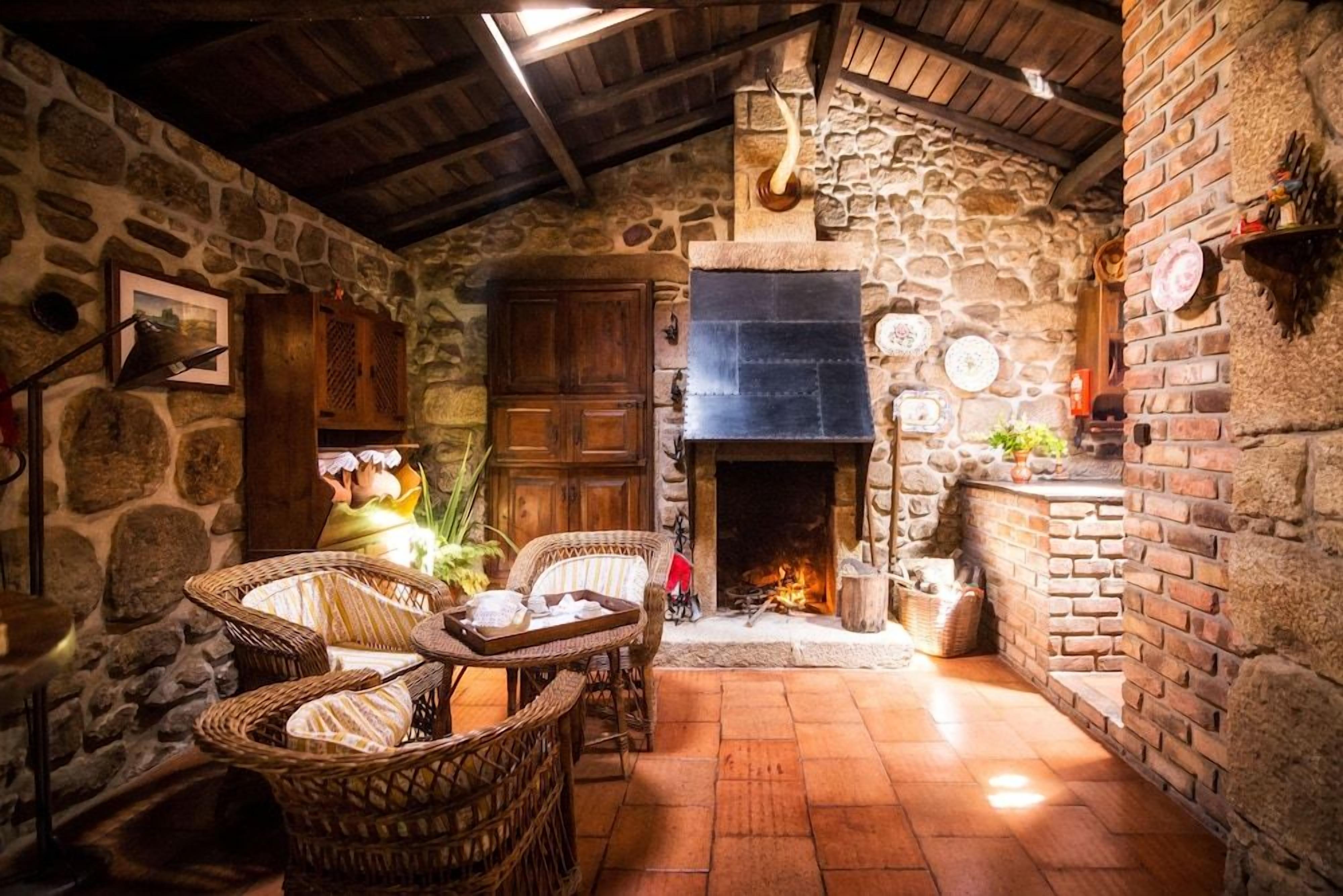 Un interior rústico de piedra con chimenea, muebles de mimbre y una pared de piedra.