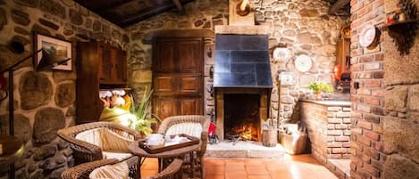Un interior rústico de piedra con chimenea, muebles de mimbre y una pared de piedra.