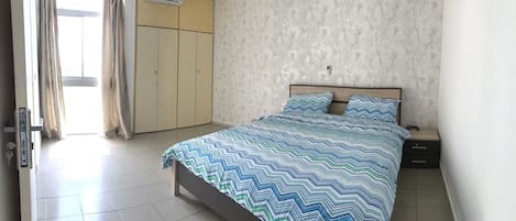 Un dormitorio con cama, mesitas de noche, armario y aire acondicionado.