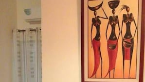 A dining area with a round table and four chairs. A framed artwork is on the wall above the table. - Residence Moneuse (Abidjan)