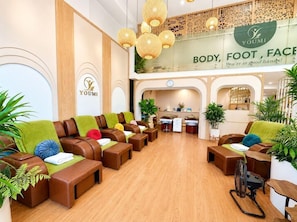A reception area with a seating area, a reception desk, and a sign that reads 'YOMI BODY, FOOT, FACE'. - A25 Hotel 19 Cha Ca (Hanoi)