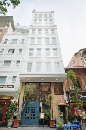 Ein mehrstöckiges Hotel mit zentralem Eingang, einem gut sichtbaren Schild für das 'CENTRAL HOTEL' und einem Schild für 'VIEW HOTEL' auf der linken Seite.