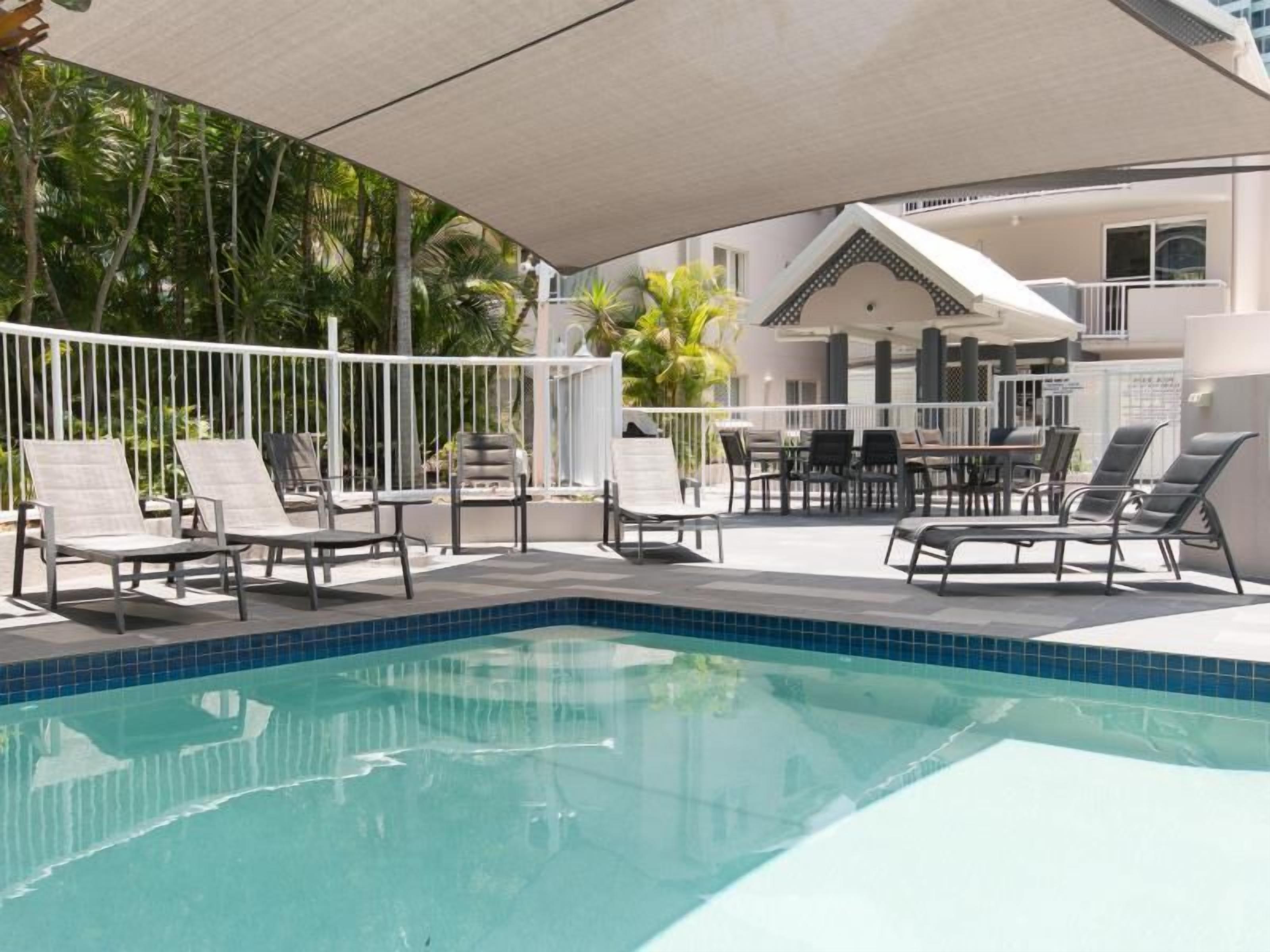 Une piscine avec des chaises longues et un espace salon abrité.