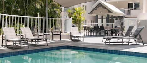 A swimming pool with lounge chairs and a covered seating area.