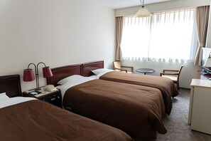A hotel room with two beds, a desk, a chair, a lamp, and a television. - New Tanda (Nagasaki)
